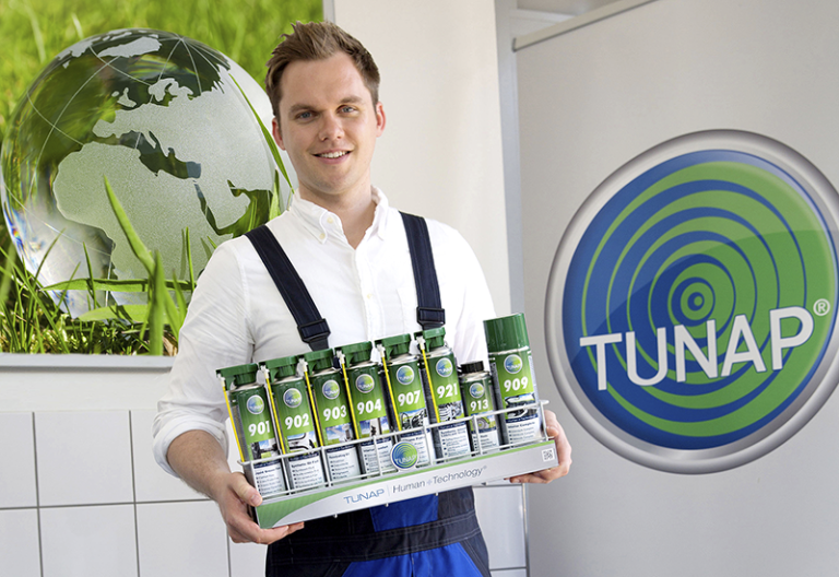 Human Technology Ung mekaniker som bærer et sett matchende grønne sprayflasker